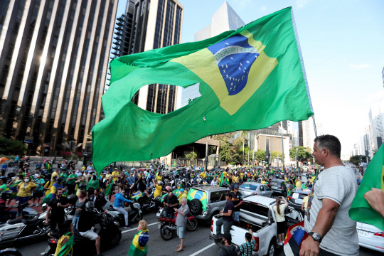 브라질 "봉쇄 풀라" 시위  브라질 상파울루에서 19일(현지시간) 신종 코로나바이러스 감염증(코로나19) 확산 방지를 위한 격리 조처에 반대하며 군부 개입을 주장하는 시민들이 차량 시위를 벌이고 있다. 자이르 보우소나루 대통령은 이날 '사회적 거리 두기' 권고를 무시하고 브라질리아 육군본부 앞에서 열린 지지자 집회에 참석해 연설했다.  상파울루=EPA 연합뉴스